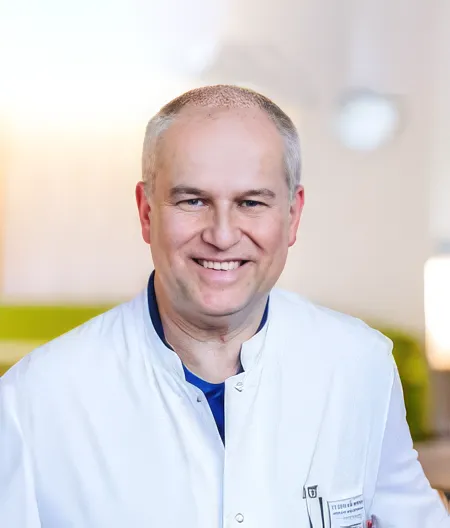 Peters_Klaus_M Photos of a smiling, bald man wearing a doctor's coat